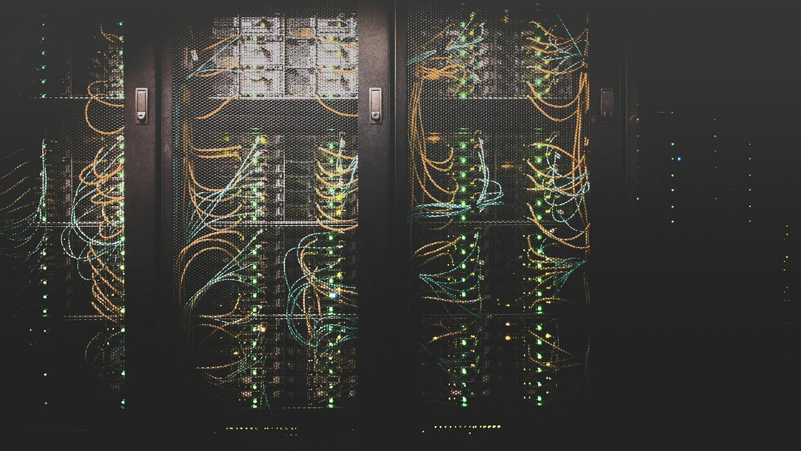 Rows of server hardware with colorful network cables in a dark data center