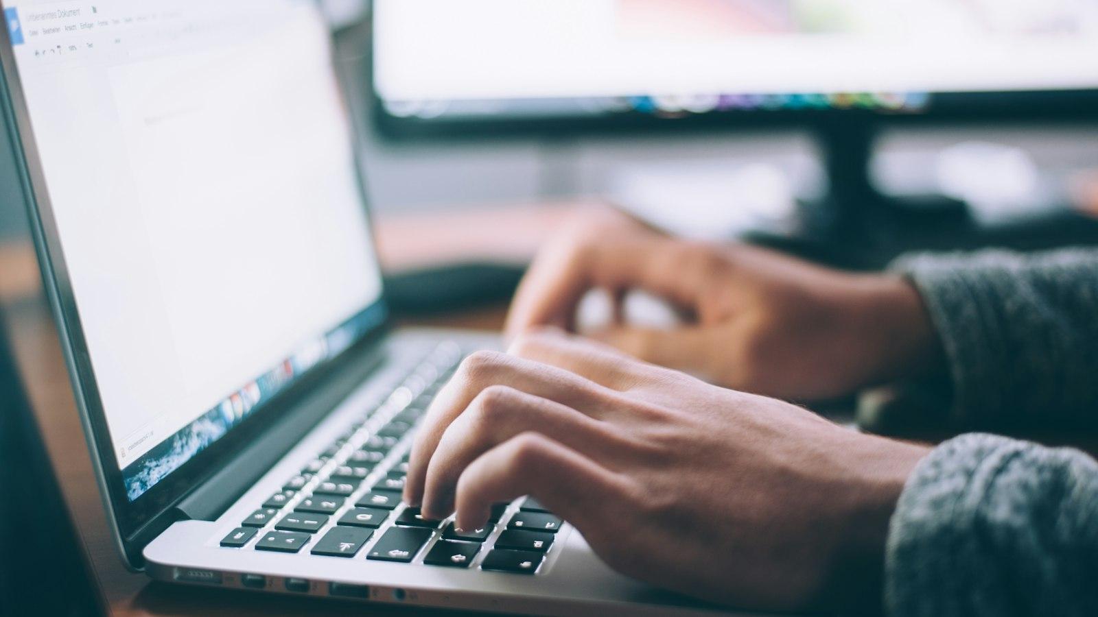 Hands typing on a laptop keyboard in soft natural light
